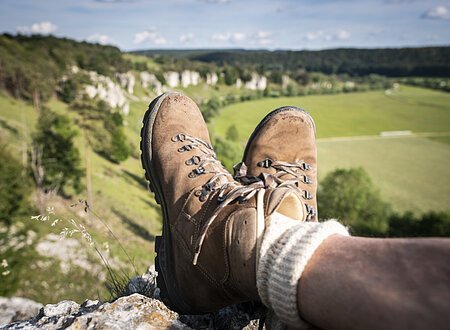 Die 12 Apostel bei Solnhofen Braune Wanderschuhe mit hellen Socken sind im Mittelpunkt. Dahinter erstrecken sich die zwölf Apostel, die am Altmühltal-Panoramaweg liegen.